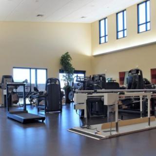 A spacious gym with various exercise equipment and bright natural lighting.