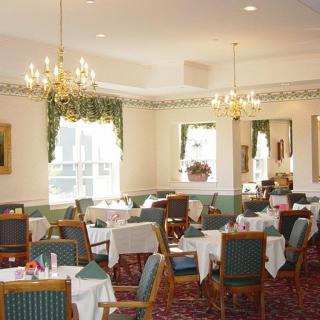 An elegant dining room with neatly arranged tables and chandeliers.