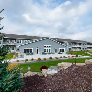 A modern residential apartment complex with landscaped gardens under a cloudy sky.