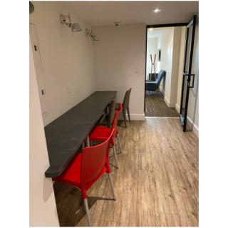 A modern workspace featuring a long table and red chairs, designed for productivity.