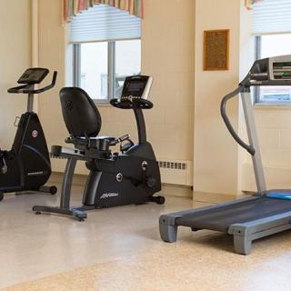 A gym room featuring a treadmill and stationary bikes.