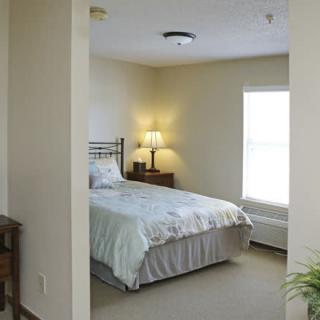 A cozy bedroom with a bed, lamp, and window.