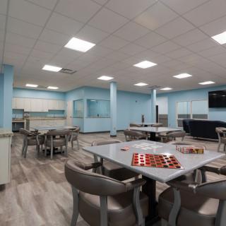 A modern multi-purpose room with tables, chairs, and games.