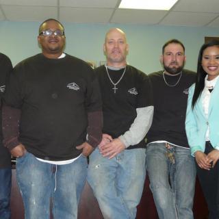 A group of people in casual attire smiling in an office setting.