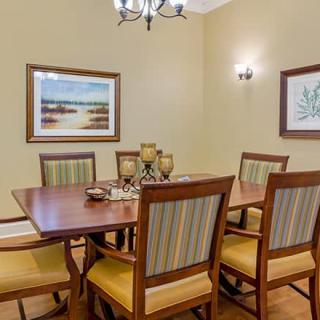 A cozy dining room with a wooden table and chairs, adorned with artwork and elegant lighting.
