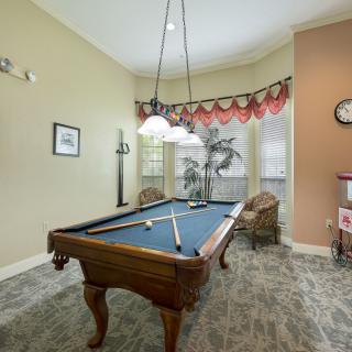 A well-lit game room featuring a billiard table with cues and balls ready for play.