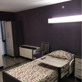A modern bedroom featuring a single bed, minimalist furniture, and a purple accent wall.