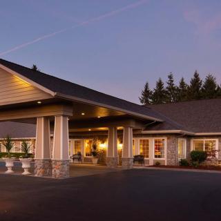A well-lit building entrance surrounded by trees at dusk.