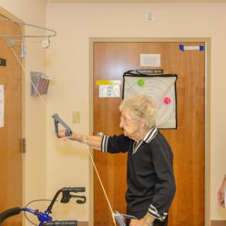 An elderly woman using a device, possibly for communication or health monitoring, in a healthcare facility.