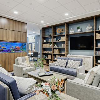 A modern living room with comfortable sofas, a large bookshelf, and an aquarium.