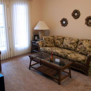 A cozy living room with a floral sofa and a glass coffee table.