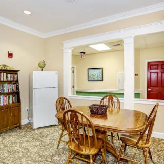 A cozy dining area with a wooden table and chairs, a bookshelf, and a refrigerator.