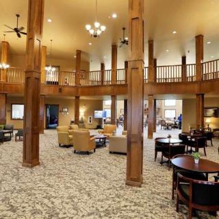 A spacious lobby with comfortable seating, wooden columns, and elegant chandeliers.