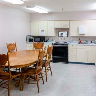 A kitchen and dining area with a wooden table, chairs, and modern appliances.