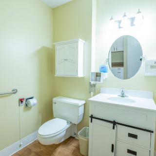 A clean and simple bathroom featuring a toilet, sink with mirror, and light fixtures.