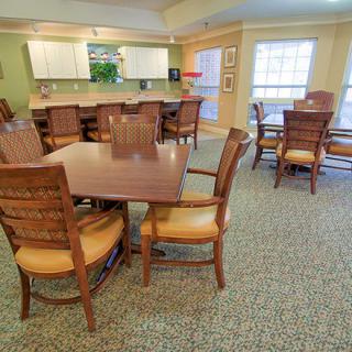 A spacious dining area with wooden tables and chairs adjacent to a kitchen.