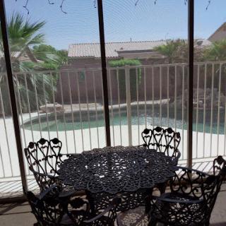 A serene view from a screened patio showcasing an intricately designed table and chairs overlooking a pool.