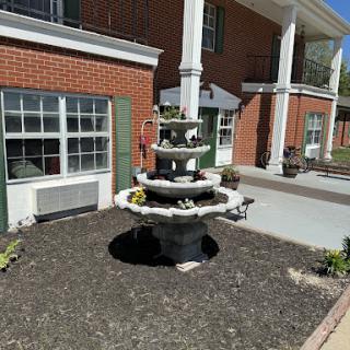 A charming multi-tiered fountain surrounded by a landscaped garden at an outdoor setting.