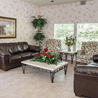 A cozy living room with leather sofas, patterned armchairs, and a marble-topped coffee table adorned with flowers.