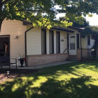 A suburban house with a well-maintained yard and trees casting shadows in the daytime.
