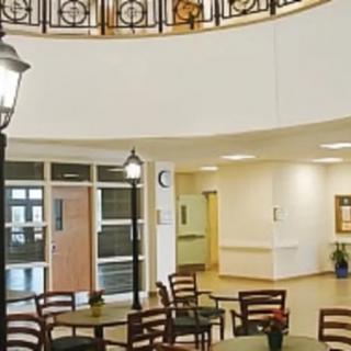 A spacious indoor area with tables and chairs, featuring a circular upper level and decorative lighting.