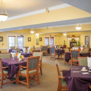 A spacious dining area with neatly arranged tables and chairs, featuring warm lighting and elegant decor.
