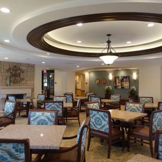 A well-furnished dining area with elegant tables and chairs, featuring a decorative chandelier and ceiling design.