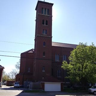 A brick church with a tall tower, illuminated by sunlight.