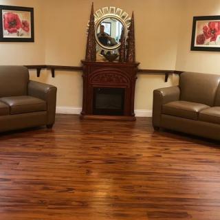 A cozy living room with two brown couches, a decorative fireplace, and wooden flooring.