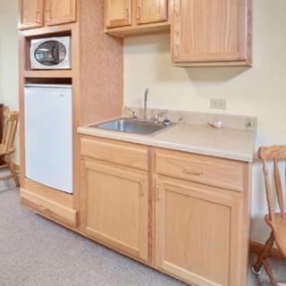 A compact kitchen area featuring wooden cabinets, a sink, a microwave, and a refrigerator.