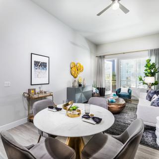 A modern living and dining area with stylish furniture, art pieces, and lush greenery.