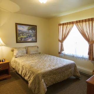 A cozy bedroom with a bed, lamp, and window with curtains.