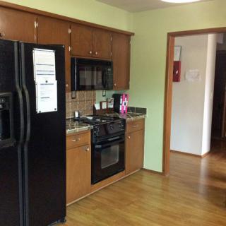 A cozy kitchen with wooden cabinets and modern appliances, including a black refrigerator, oven, and microwave.