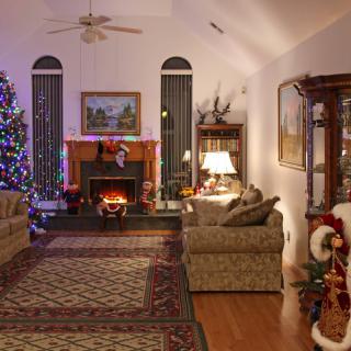 A cozy living room decorated for the Christmas season with a beautifully lit tree and a warm fireplace.