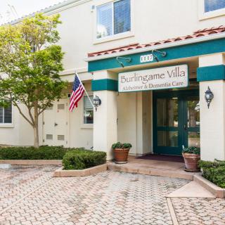 Entrance to a building with a sign, American flag, and potted plants.