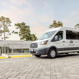 A modern transport van parked outside a contemporary building surrounded by trees.