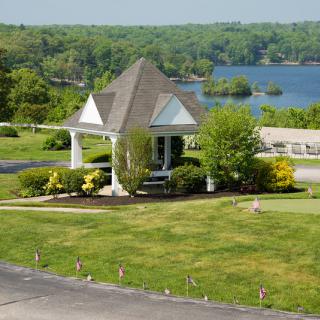 A scenic view of a gazebo overlooking a lake surrounded by lush greenery.