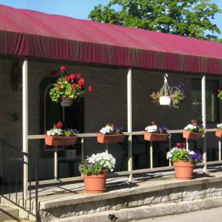 A charming building adorned with vibrant flowers in planters, featuring a red awning.