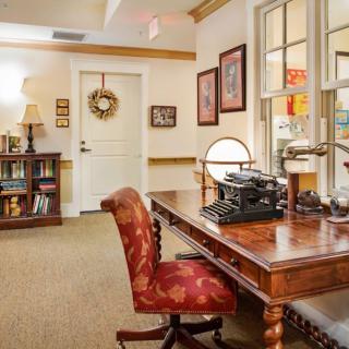 A vintage-style office with a wooden desk, typewriter, and decorated interior.