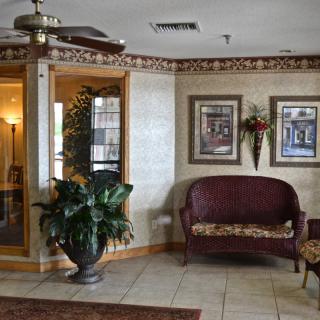 A cozy lobby area featuring a sofa, potted plants, and framed artwork on the walls.