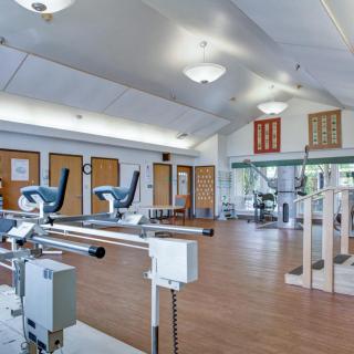 A spacious and well-lit gym with various exercise equipment.