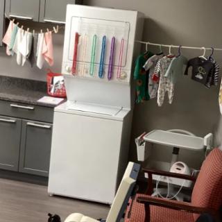 A laundry setup with clothes hanging to dry and a washing machine in a kitchen area.