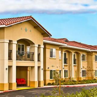 A modern residential building with a light-colored facade and red roof tiles.