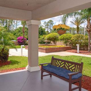 A peaceful garden patio with a bench overlooking landscaped greenery and vibrant flowers.