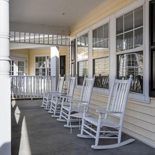 A row of white rocking chairs on a porch, providing a relaxing outdoor seating area.
