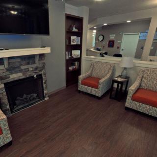 A cozy living room with a fireplace, armchairs, and a television.