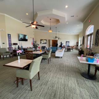 A spacious community center with tables and chairs, ceiling fans, and various decorations.