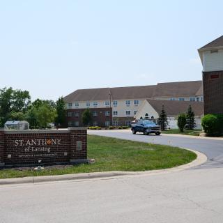 A view of a large building with a sign labeled 'St. Andrews' and a car driving on the road in front.