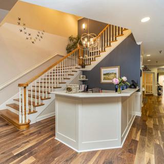 A modern interior featuring a staircase and reception desk with hardwood flooring and stylish decor.