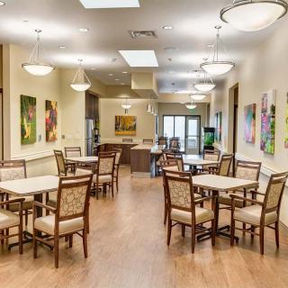 A modern dining area with multiple tables and chairs, decorated with artwork on the walls.